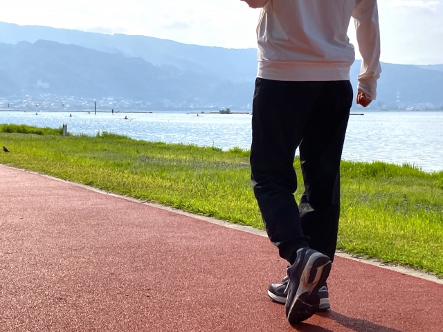 河川敷の遊歩道を歩く男性